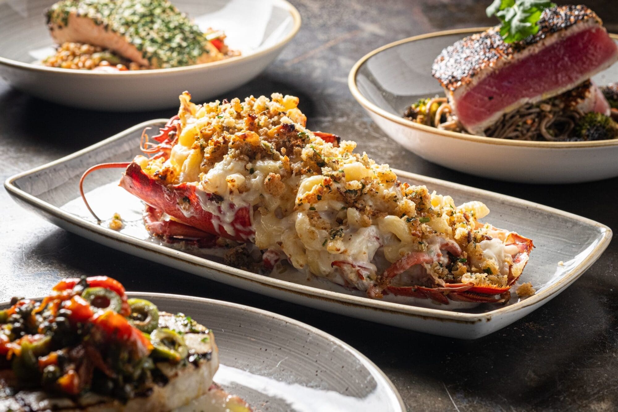 Baked Gulf of Maine lobster with shrimp and scallop stuffing, along with some other smaller plates surrounding it.