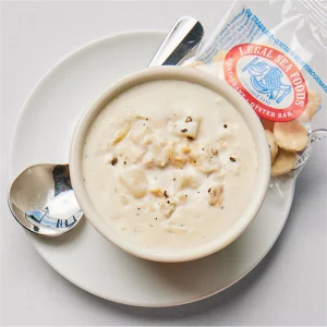 Top view of a cup of clam chowder with a spoon and oyster crackers