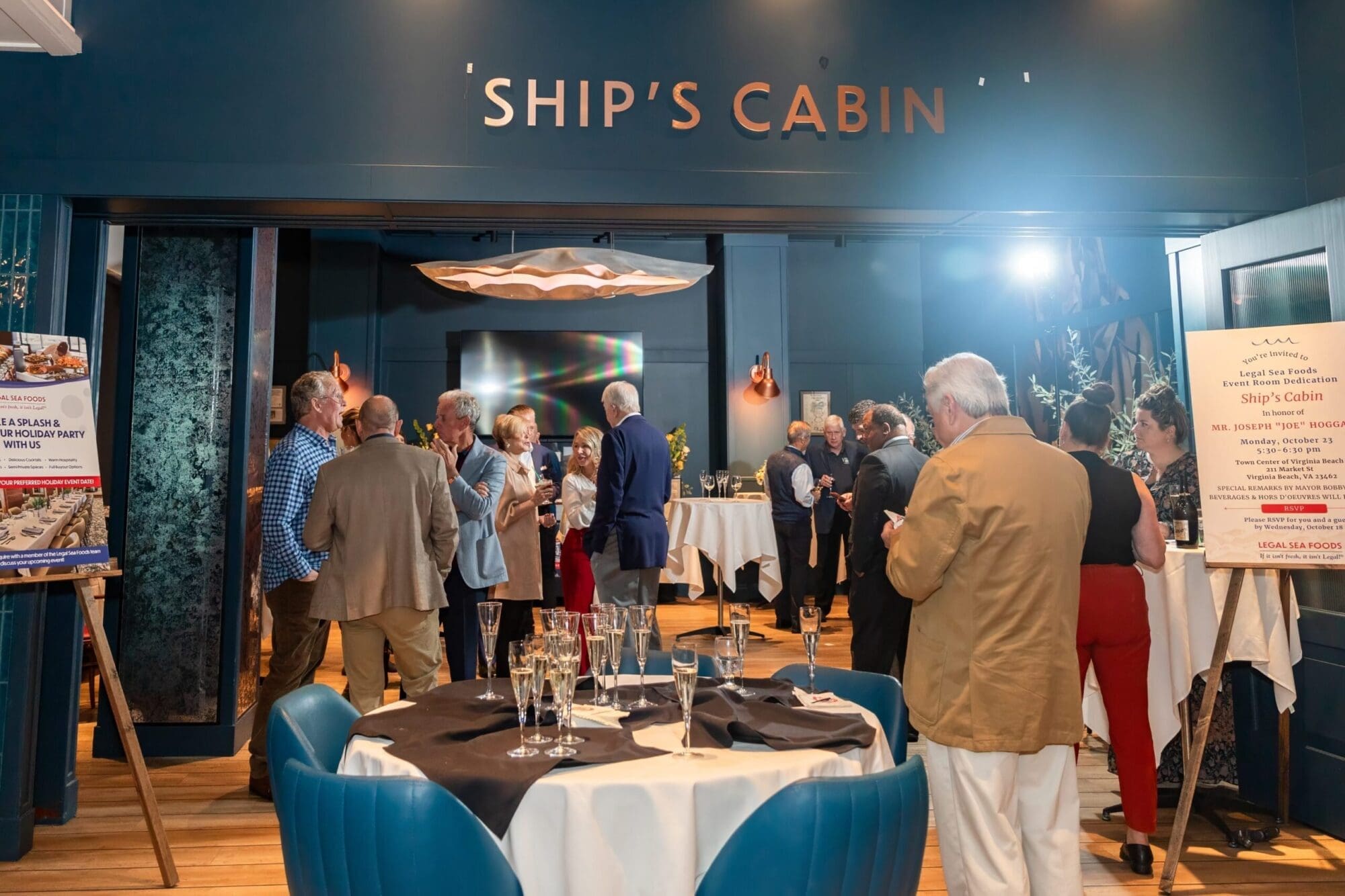 A group of people gather in a stylish room labeled 